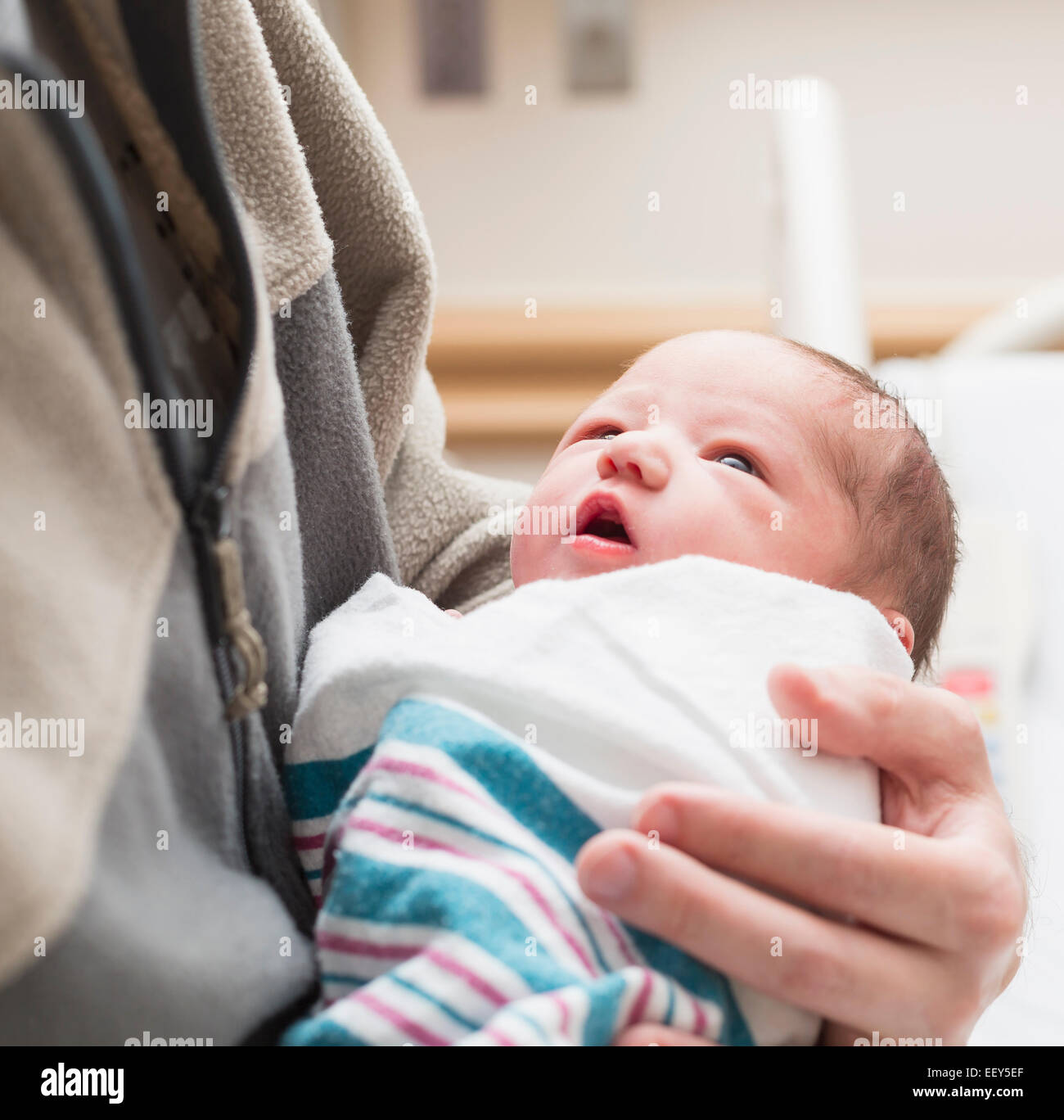 Newborn baby girl in blanket and held close by father in hospital Stock Photo