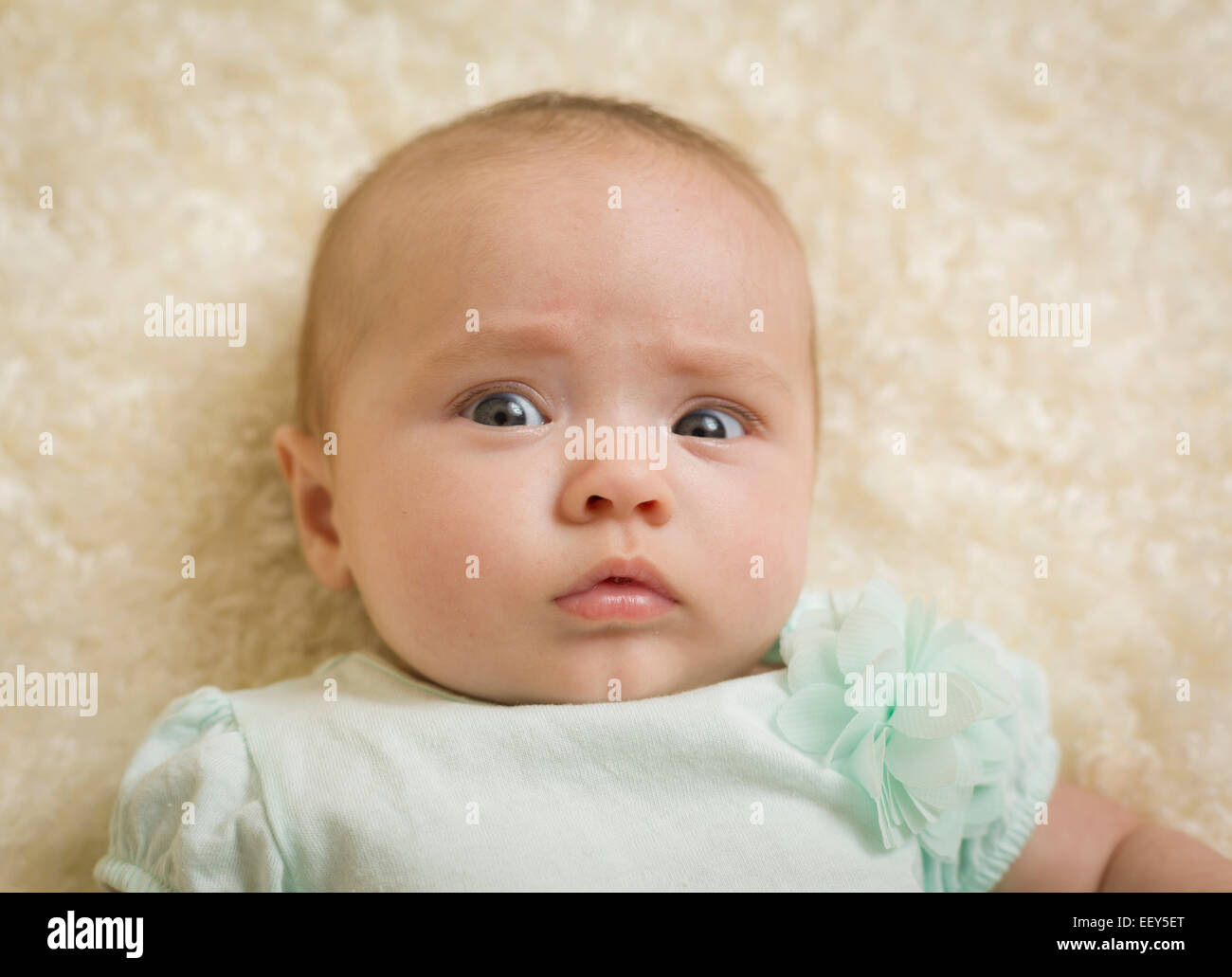 Three month old baby girl staring at camera and looking worried Stock Photo