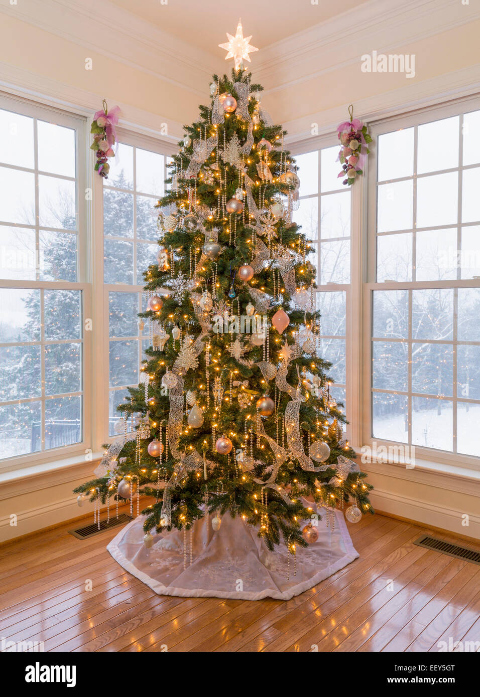 Christmas tree in modern home with snow falling outside Stock Photo