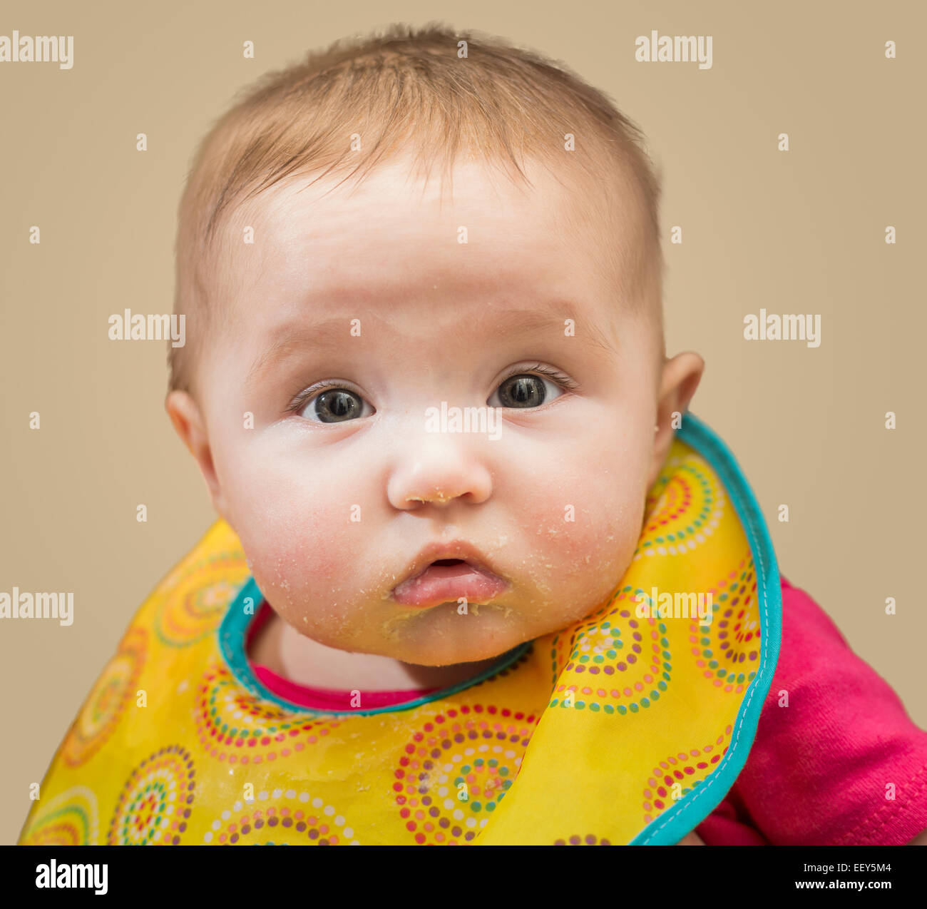 Small baby girl takes her first solid food and is unhappy with the process Stock Photo