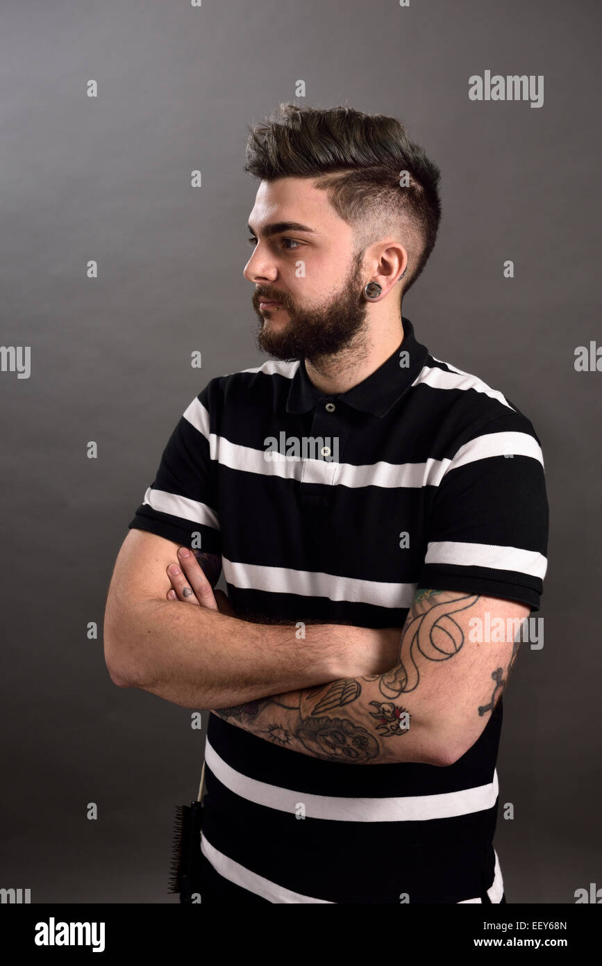 Portrait of a young male hair stylist with tattoos and piercings Stock Photo