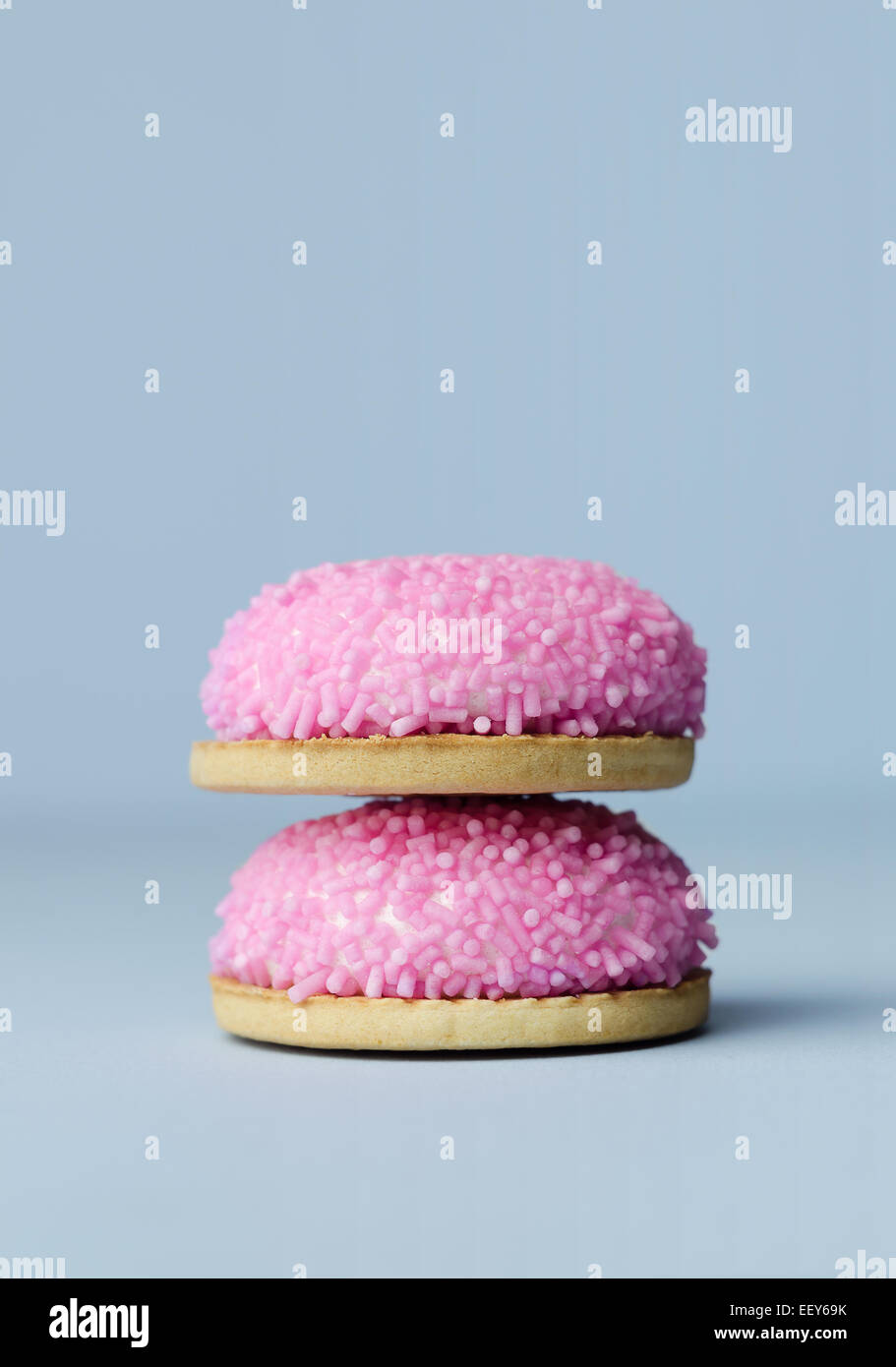 Marshmallow biscuits with pink sugar sprinkles over blue background