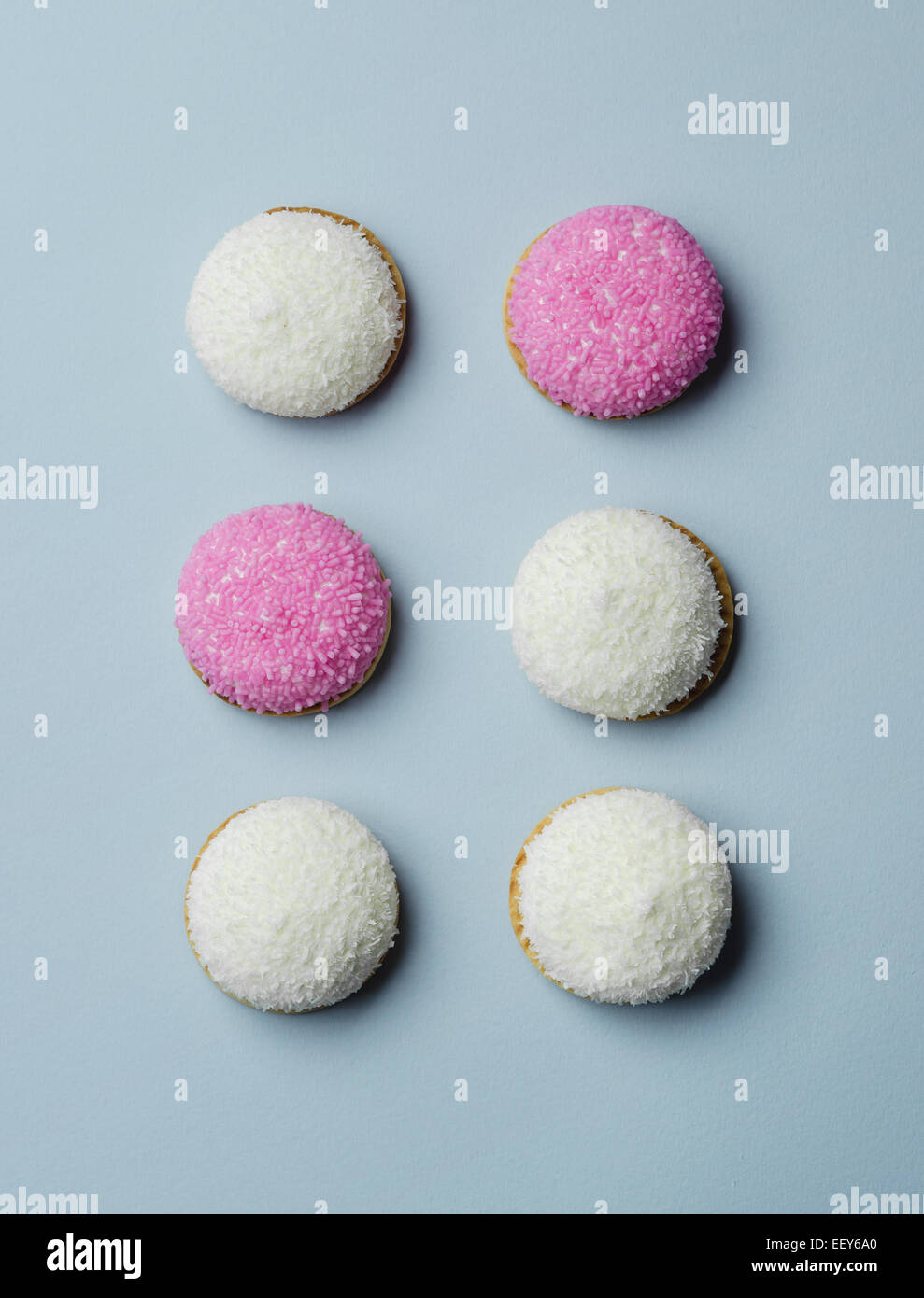 Marshmallow biscuits pink sugar and coconut sprinkles over blue background, above view Stock Photo