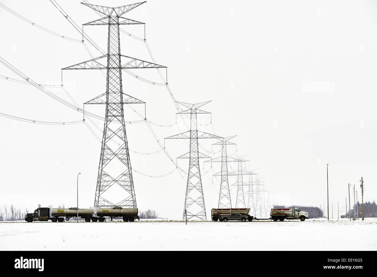 A horizontal image of vehicles traveling on a rural road under a power line Stock Photo