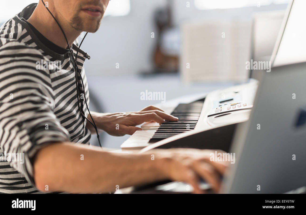 Man using laptop and synth to make music Stock Photo Alamy