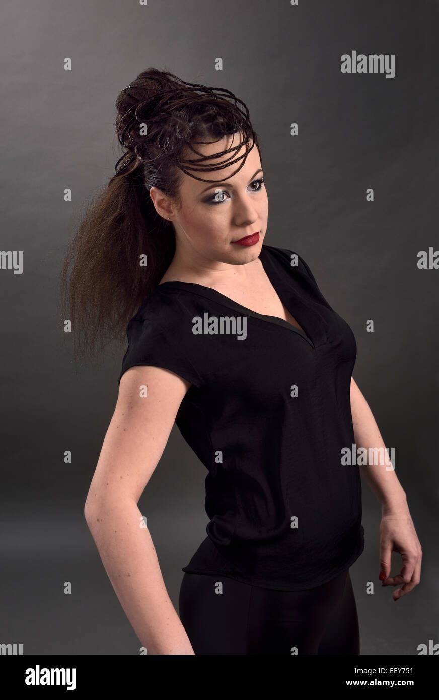 Model in black impersonating mannequin with elaborate hairstyle with braids and crimped hair Stock Photo