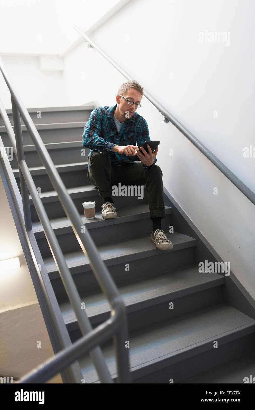 Man sitting on steps using tablet pc Stock Photo