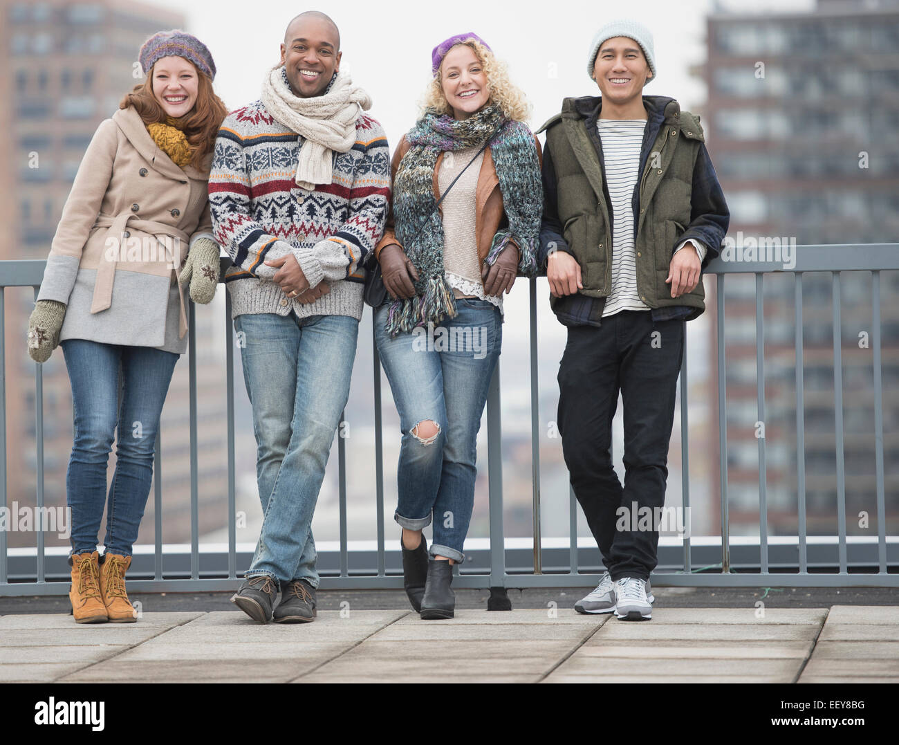 Portrait of happy friends leaning against bridge railing Stock Photo