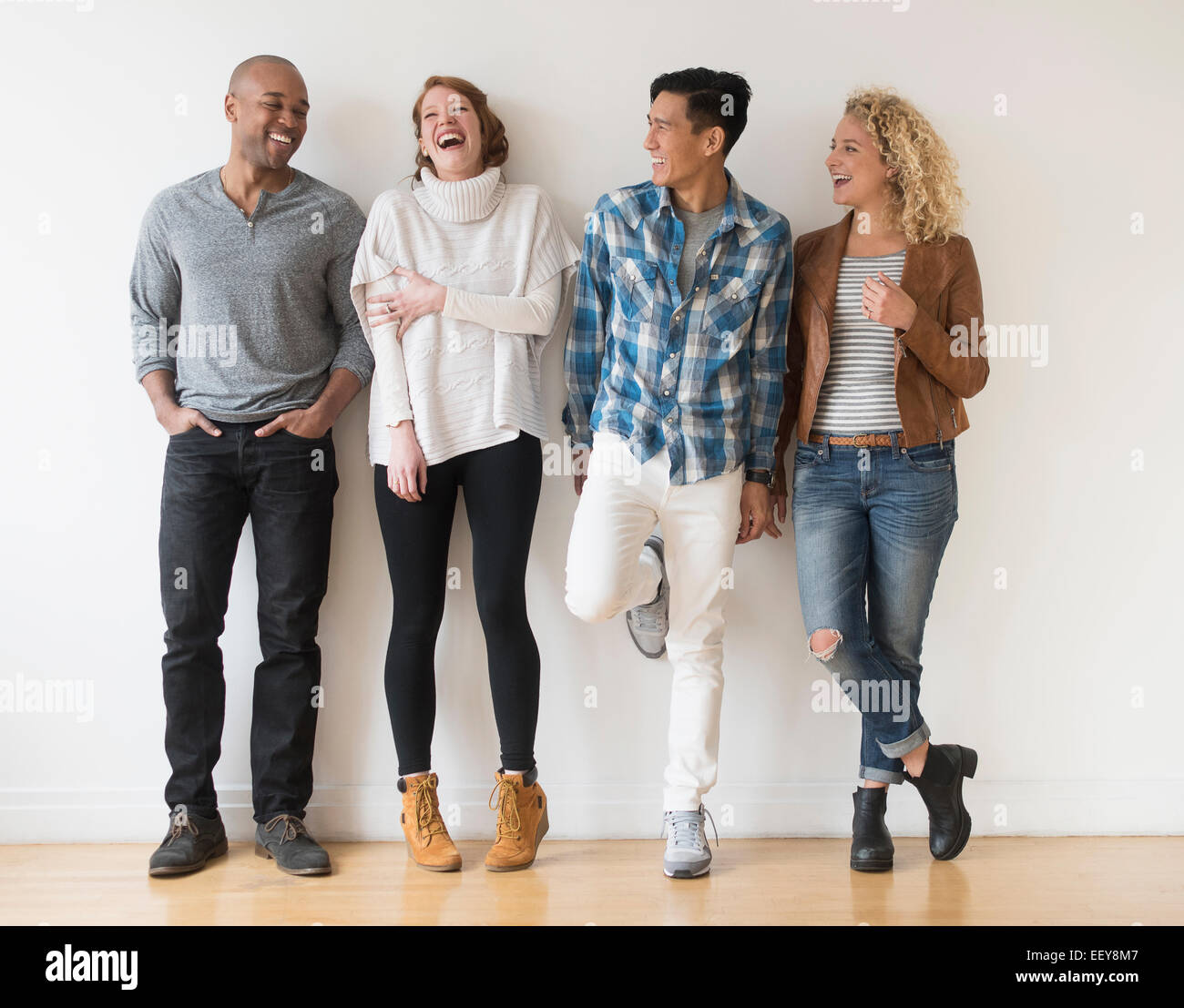 Laughing friends standing against white wall Stock Photo