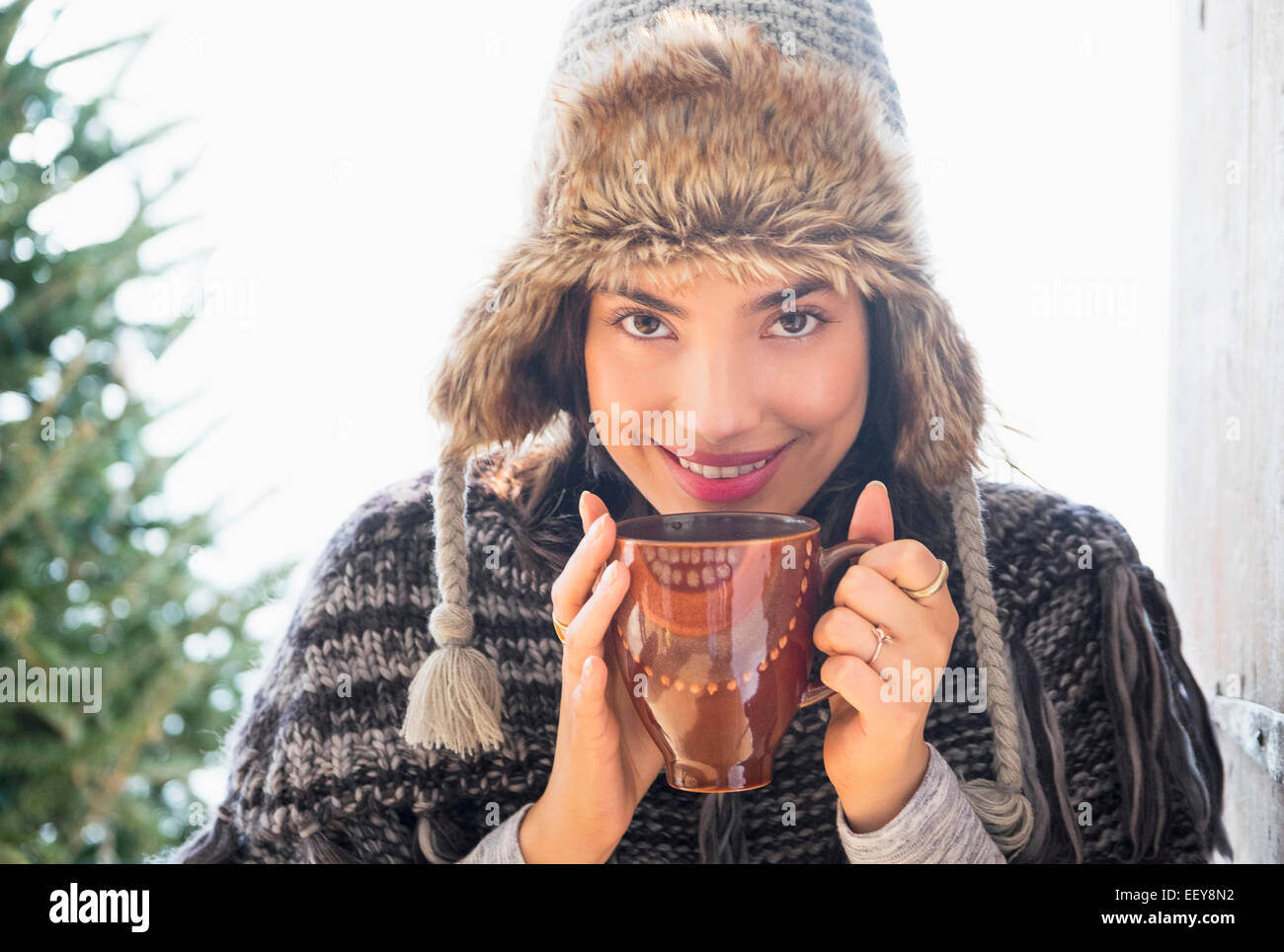 Portrait of young woman wearing winter hat, holding mug Stock Photo