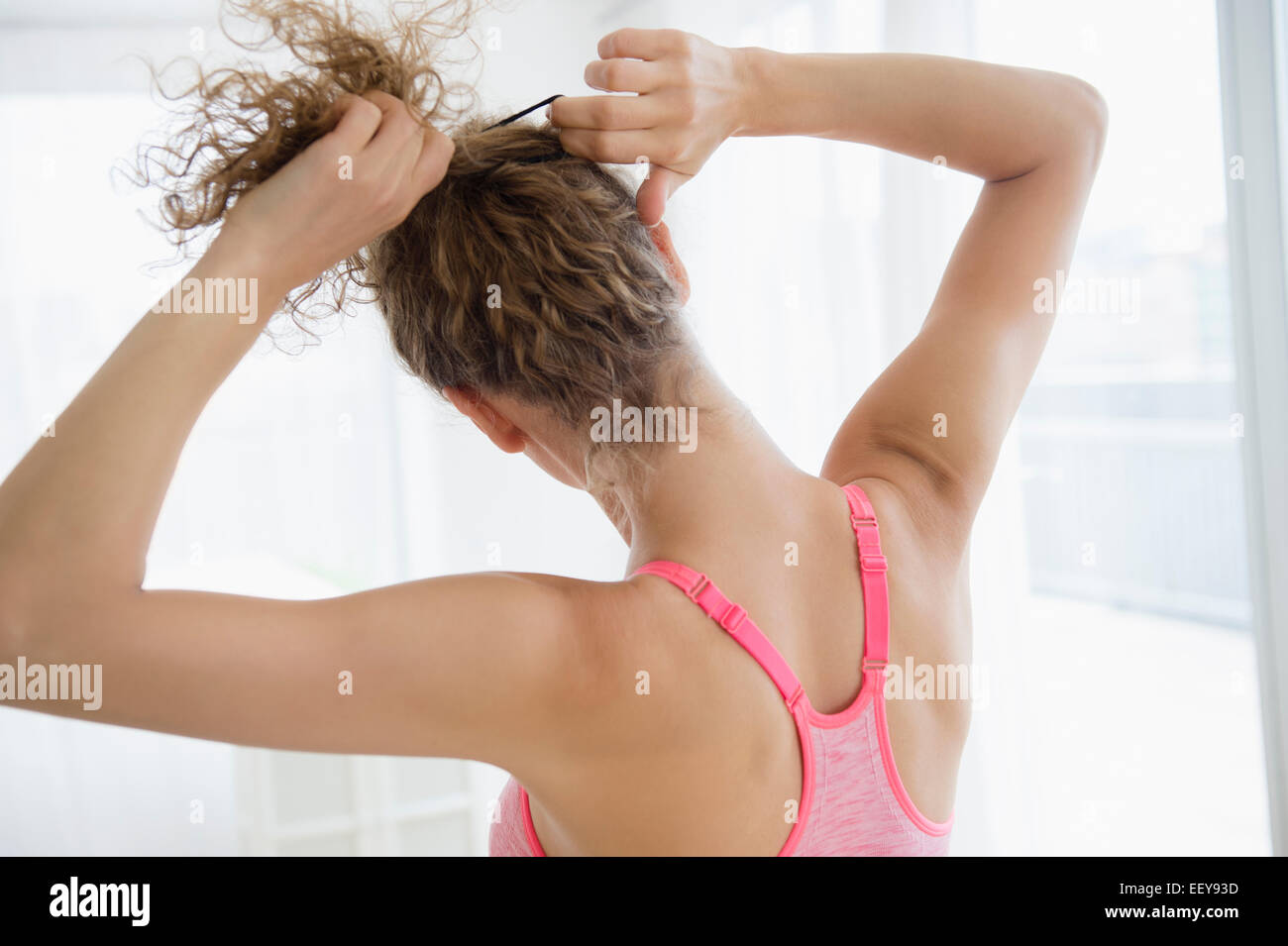 Young woman tying hair Stock Photo Alamy