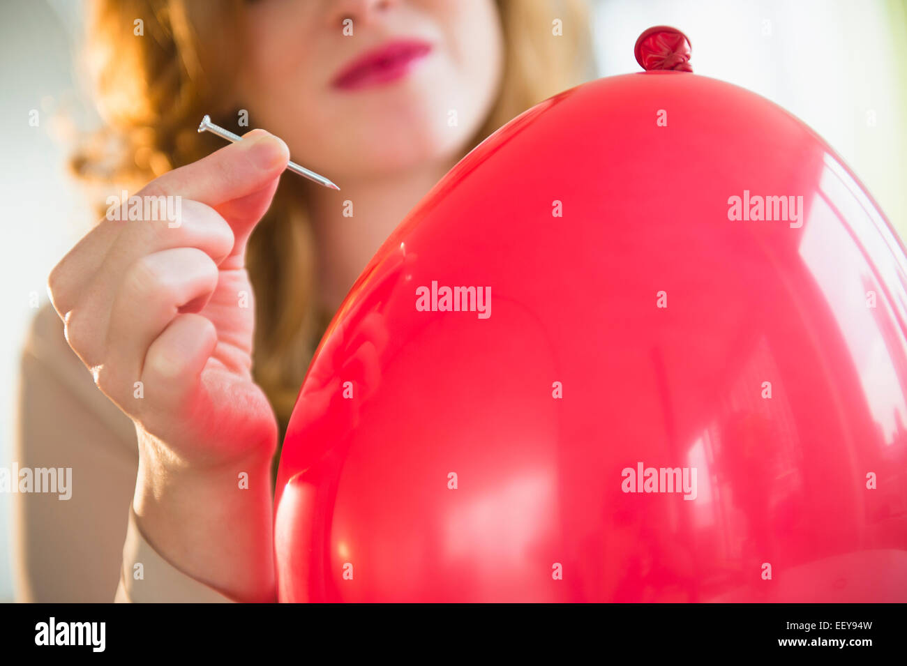 Young woman popping balloon Stock Photo