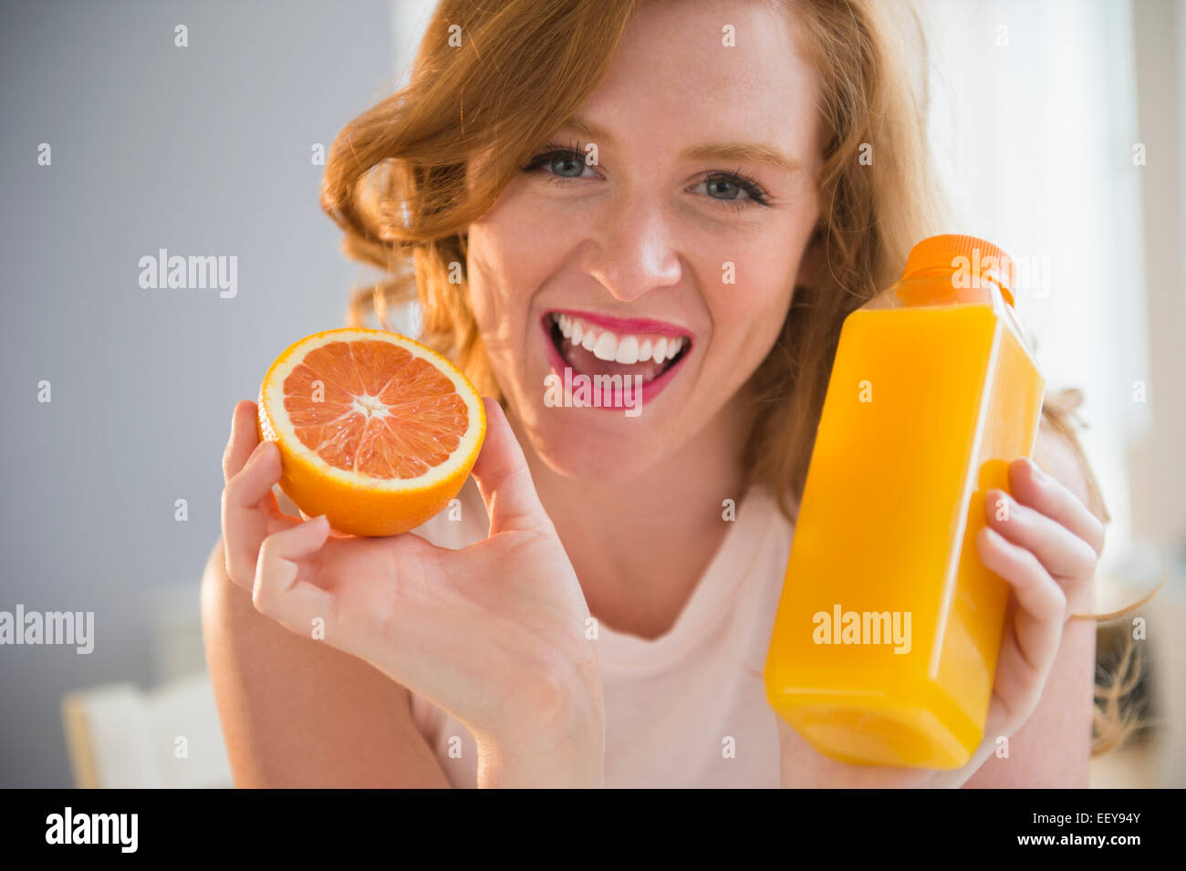 Portrait of woman holding orange and orange juice Stock Photo