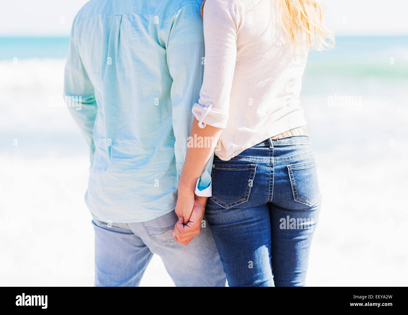 Man and woman holding hands on beach Stock Photo - Alamy