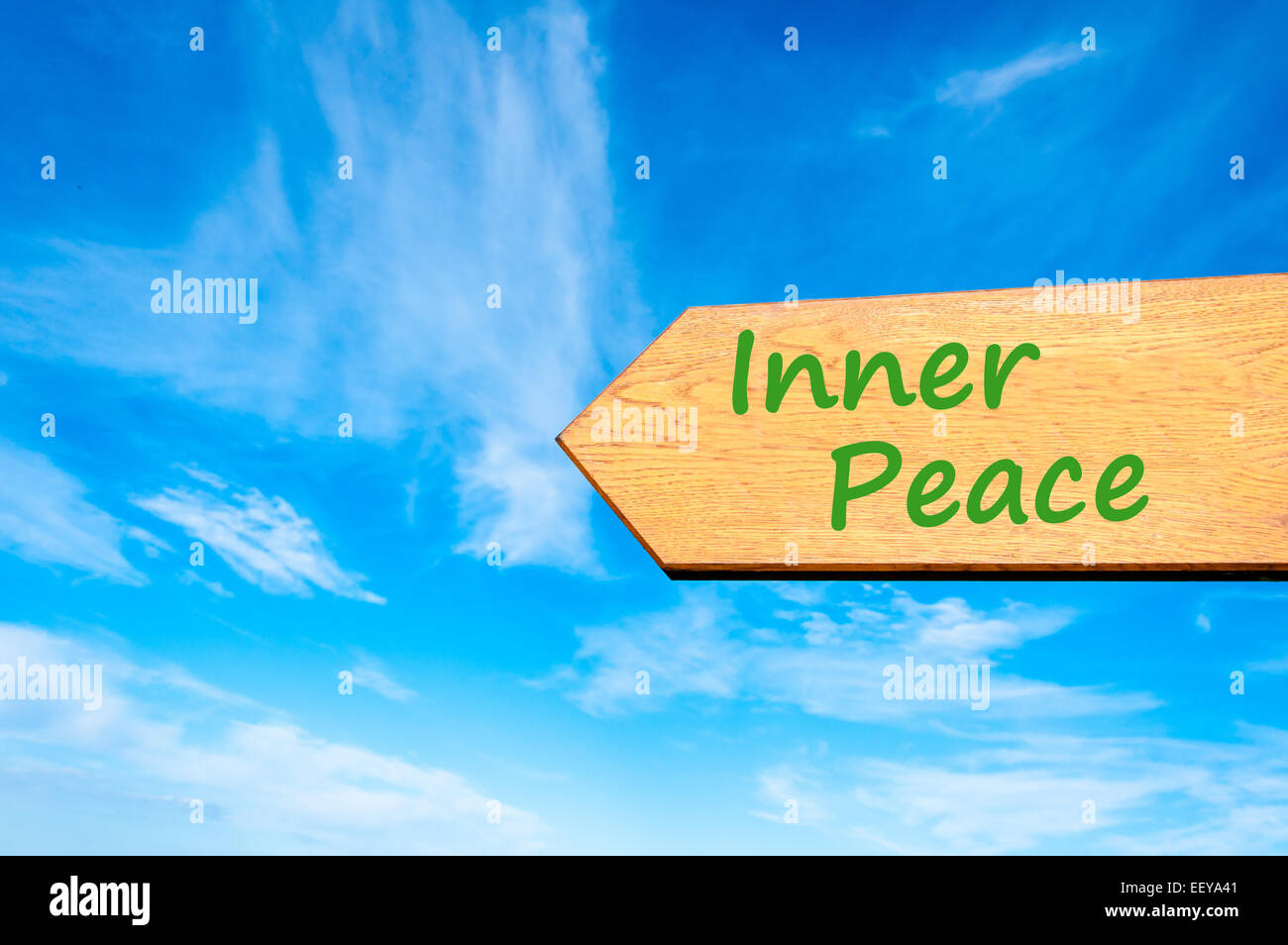 Wood arrow sign against clear blue sky with Inner Peace message Stock Photo