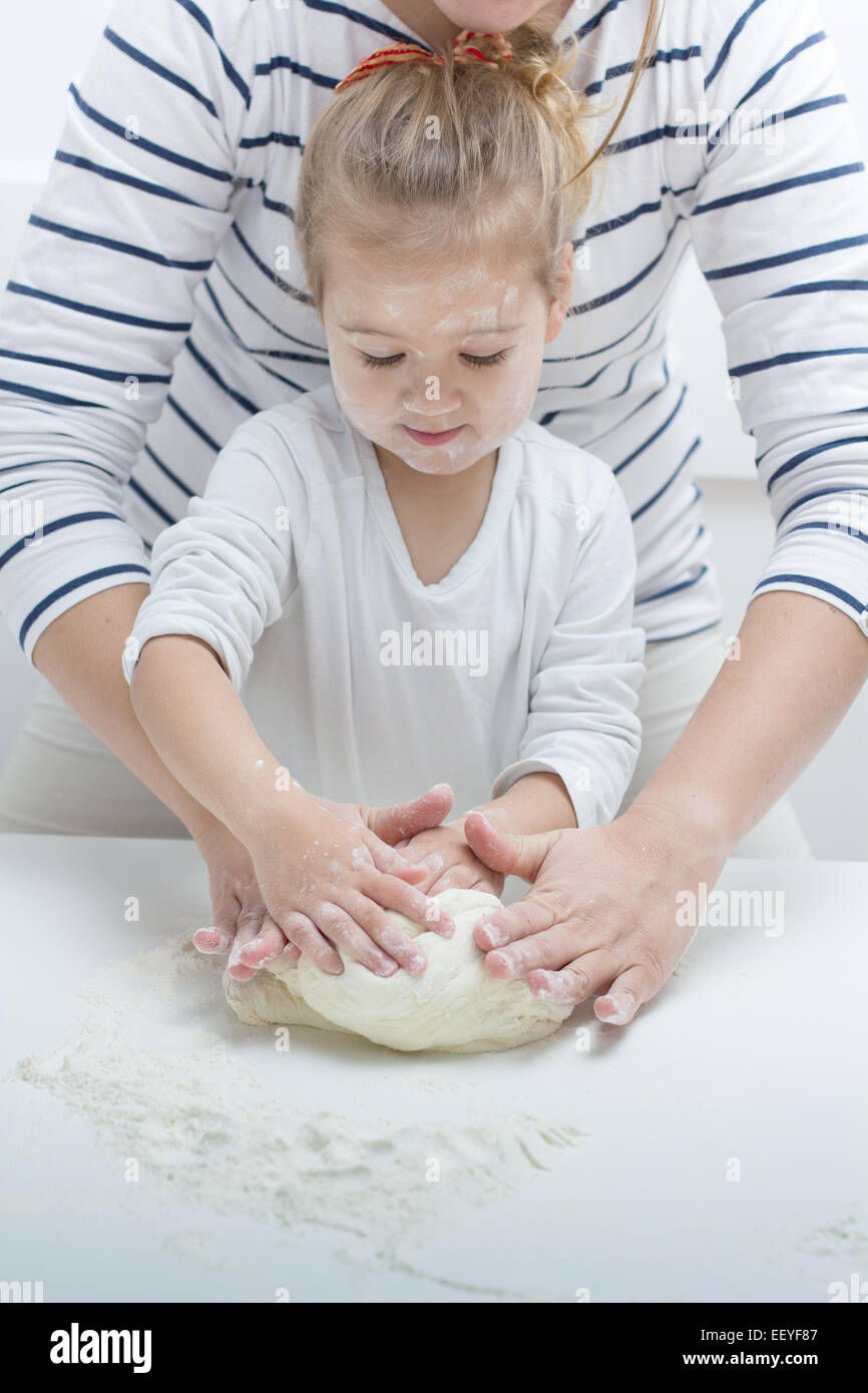 Cute little girl with her mother kneading dough at home Stock Photo - Alamy