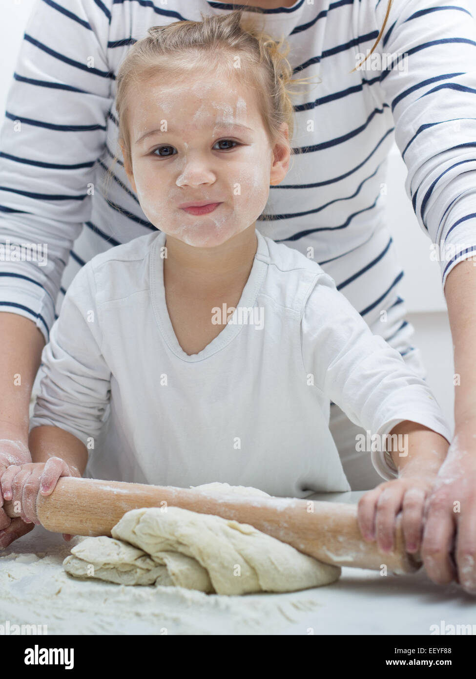 Cute little girl with her mother kneading dough at home Stock Photo - Alamy