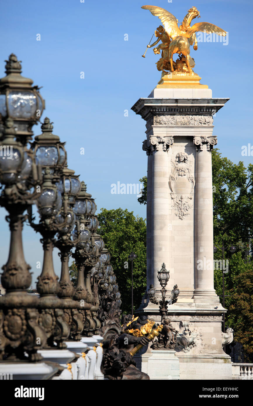 Ornate renaissance street lamps on the famous Pont Alexandre III bridge in central Paris with golden gateway statue Stock Photo