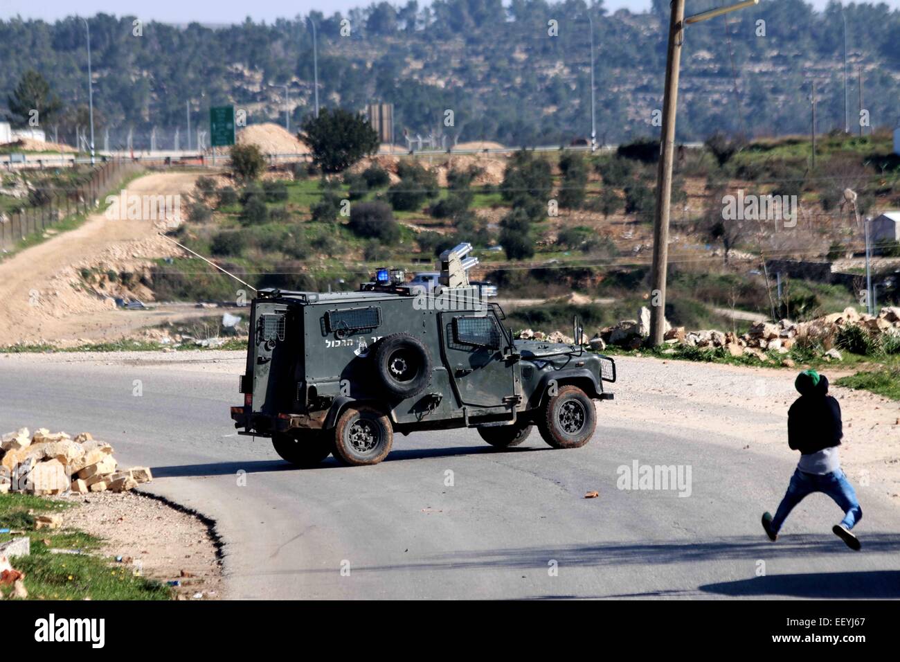 A Palestiinan youth pelts an Israeli army jeeps with rocks. The jeep
