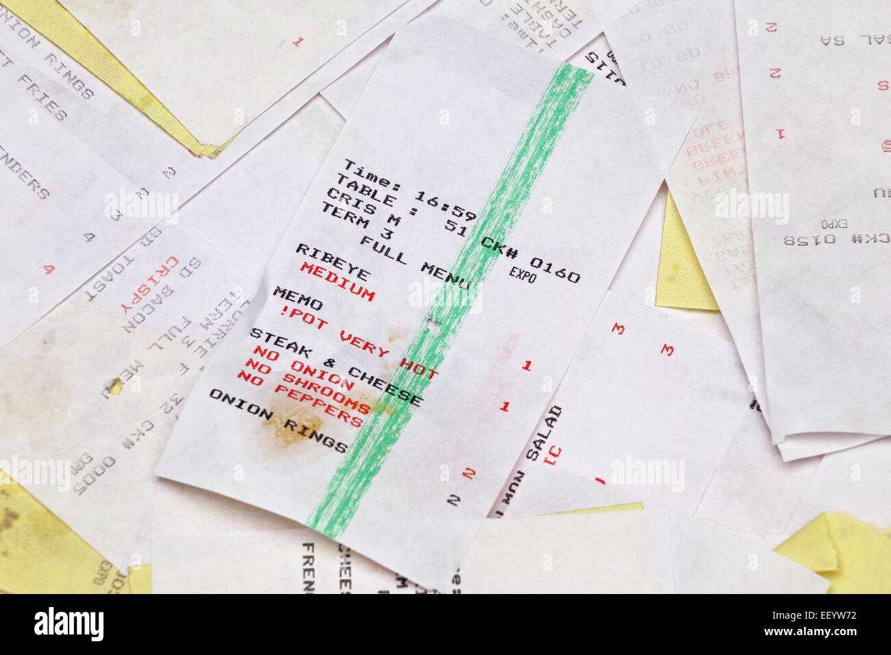 Yellow and white grease stained restaurant food order tickets in a pile. Stock Photo