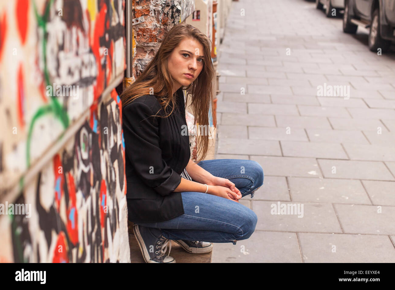 Hipster girl sitting on the street. Stock Photo