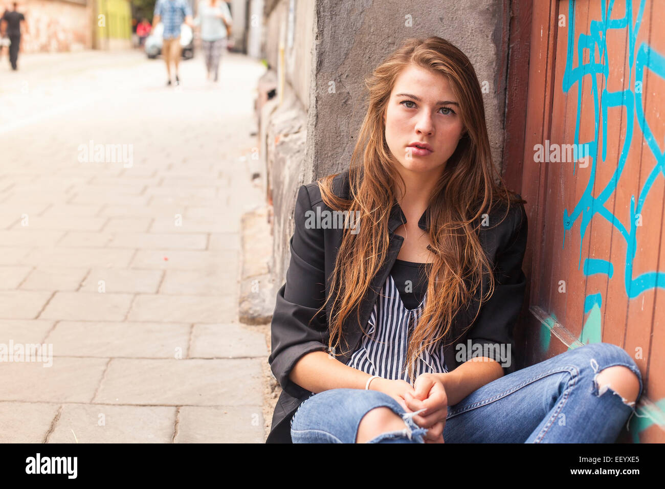 Young hipster girl sitting on the street. Stock Photo