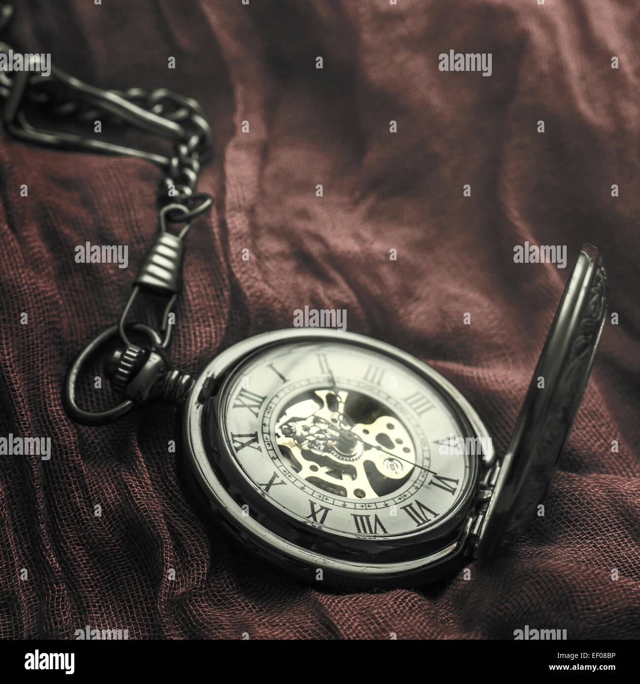 Artistic low key image of antique pocket watch on striped  fabric. Close up  with  shallow dof. Stock Photo
