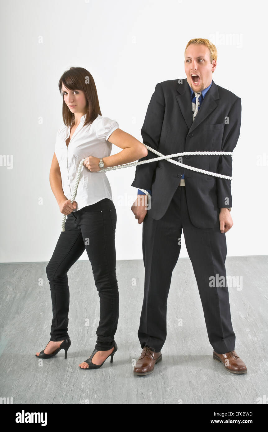 Woman holding a rope around a man Stock Photo