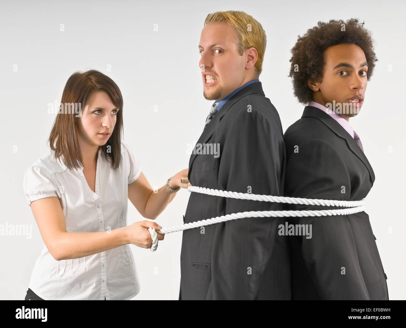 Woman tying two businessmen together with a rope Stock Photo