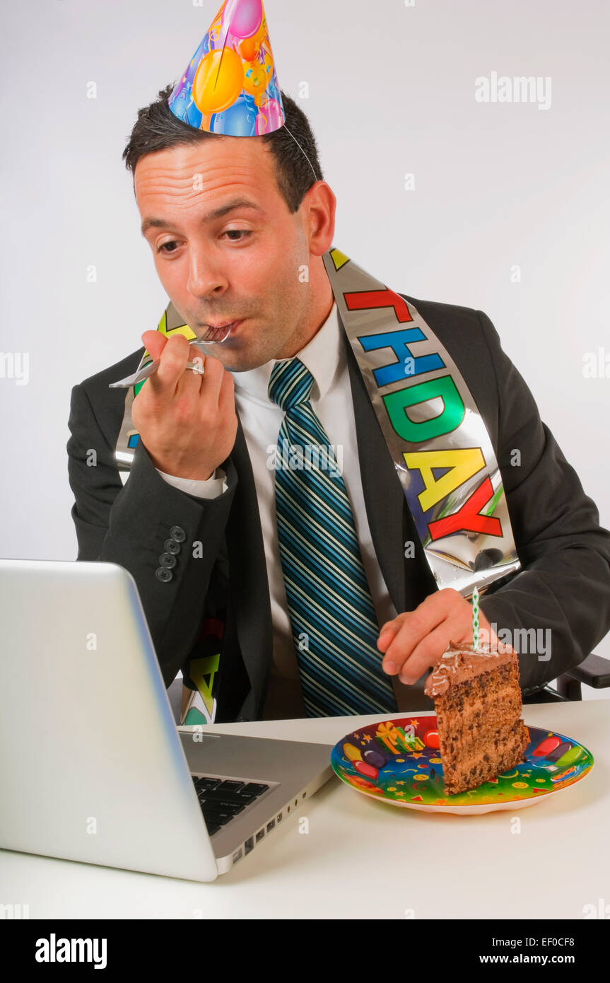 Businessman eating birthday cake at his desk Stock Photo Alamy