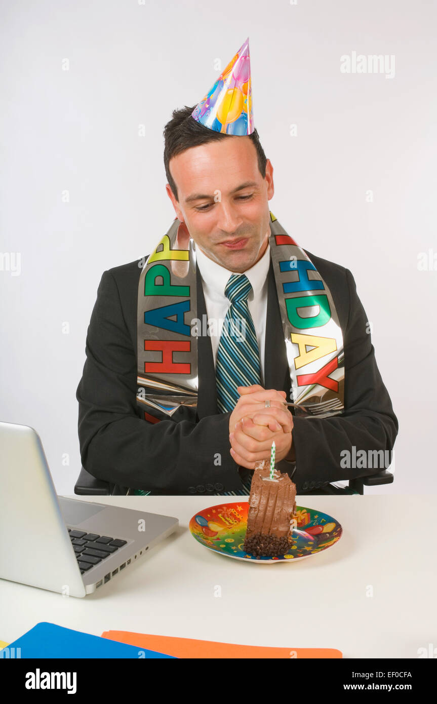 Businessman eating birthday cake at his desk Stock Photo Alamy