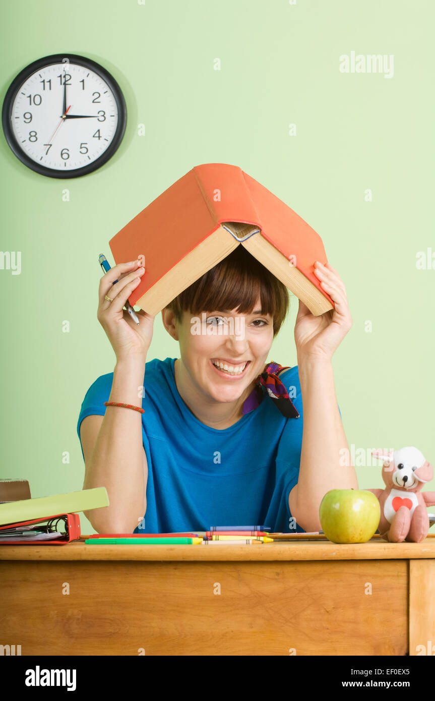 Student holding school book over her head Stock Photo - Alamy