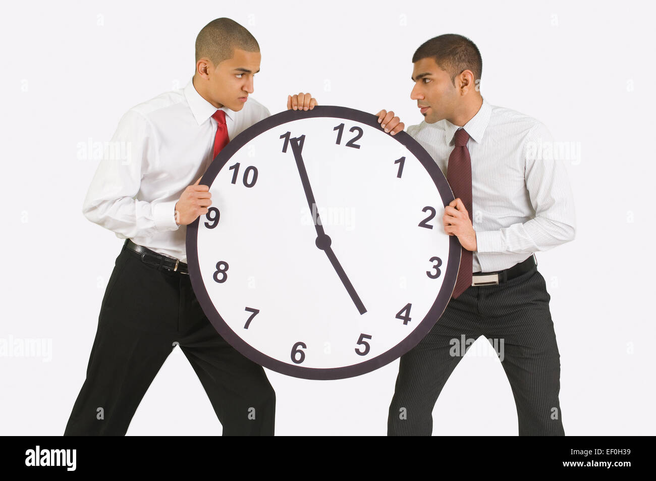 Businessmen fighting over a clock Stock Photo