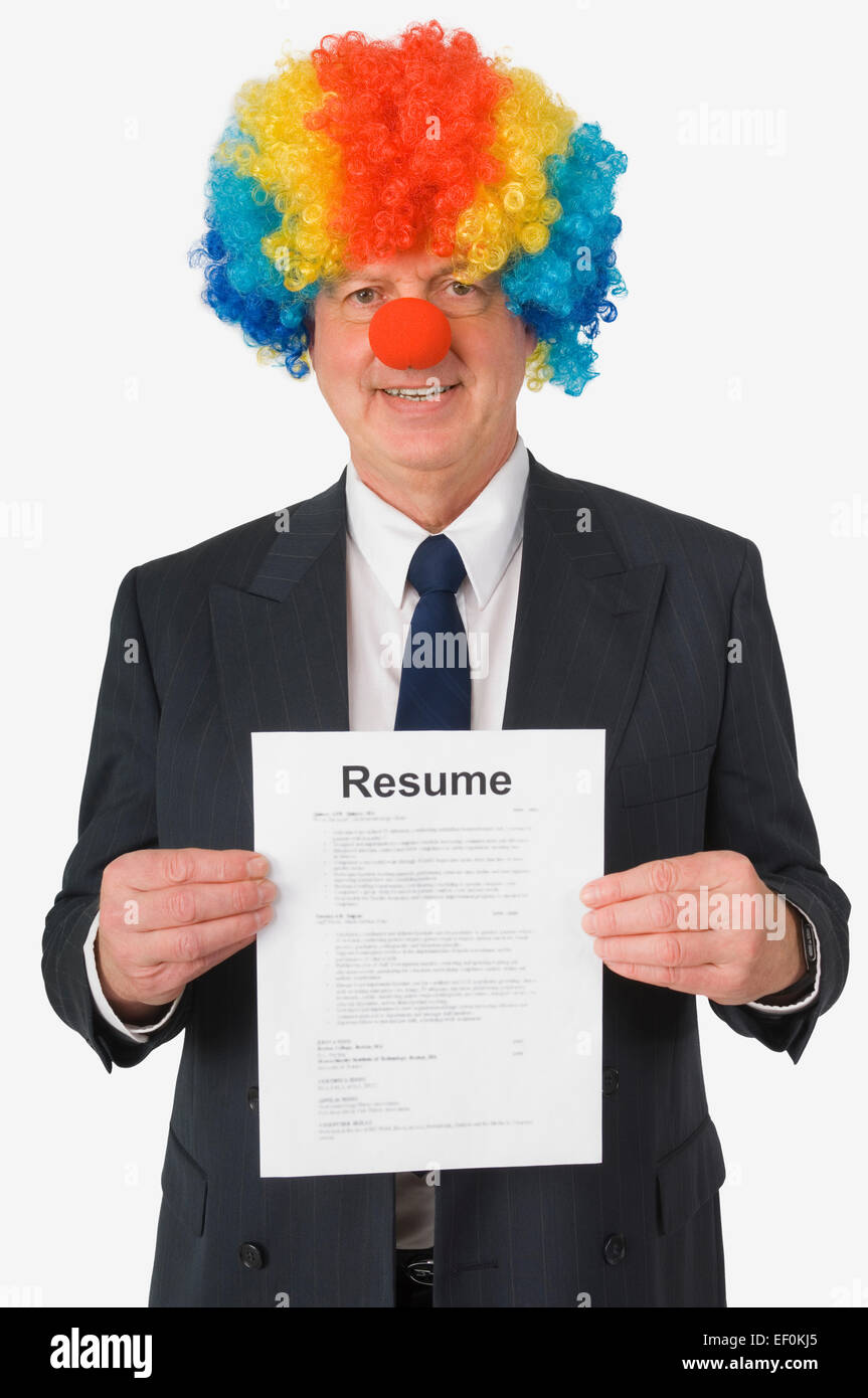 Businessman wearing clown nose and wig and holding resume Stock Photo