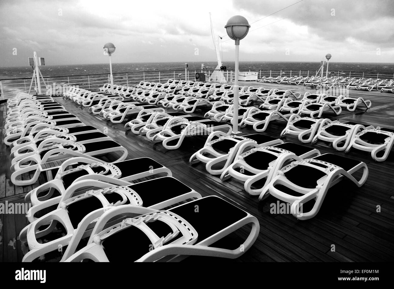 Sun loungers on a cruise ship deck in stormy seas and dramatic clouds ...