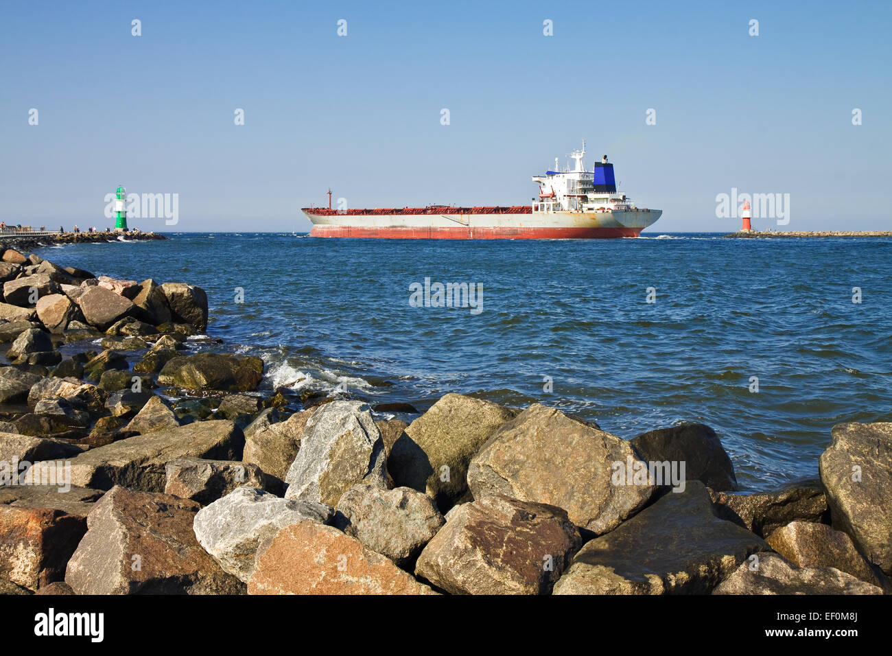 A cargo ship passes by the lighthouses of Warnemuende. Stock Photo