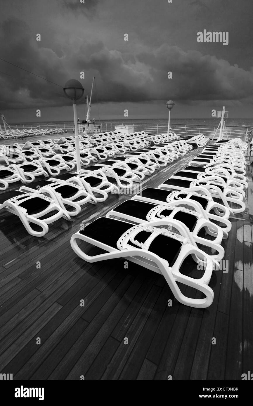 Sun loungers on a cruise ship deck in stormy seas and dramatic clouds ...