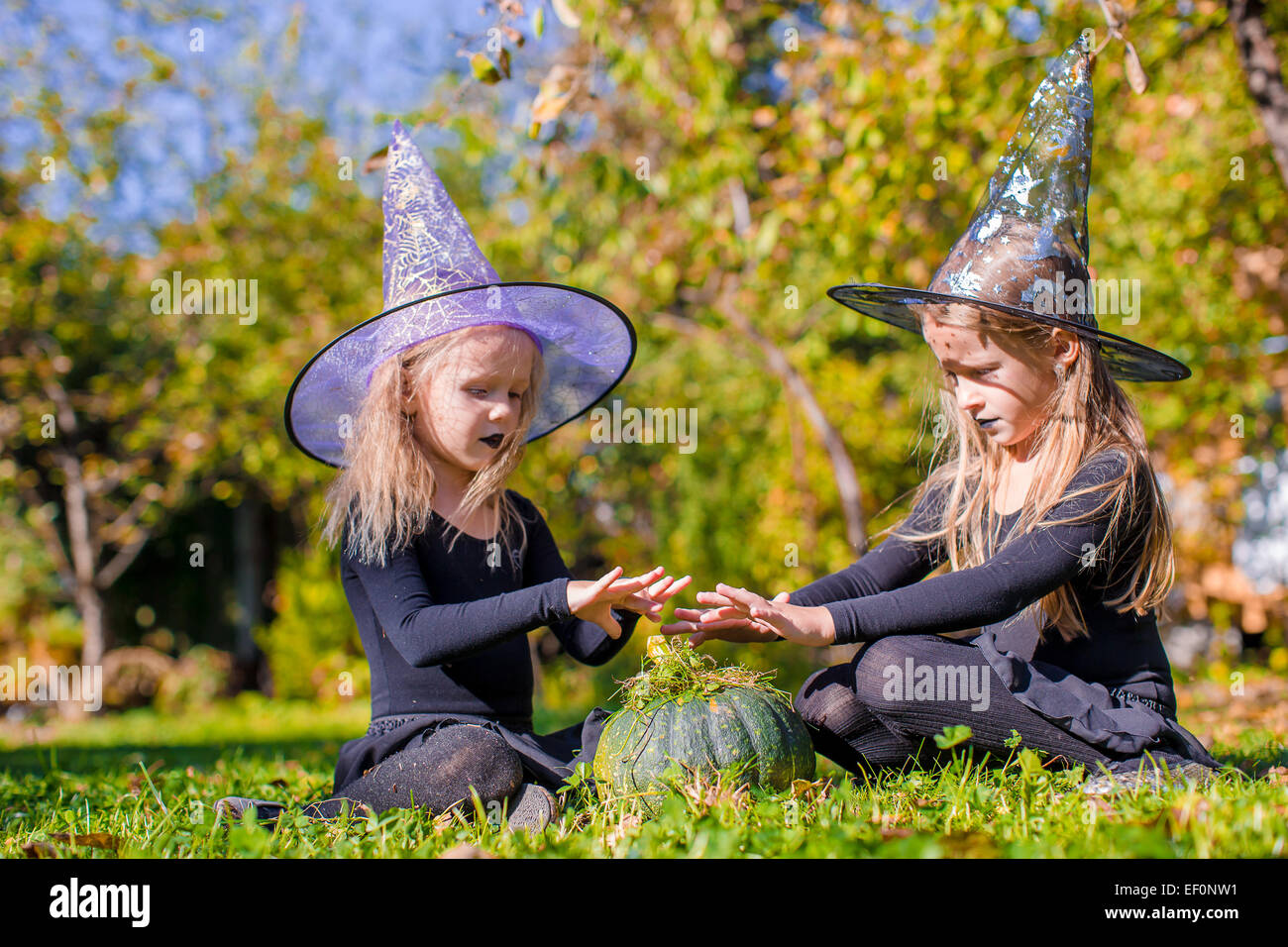 Little cute girls casting a spell on Halloween in witch costume Stock ...