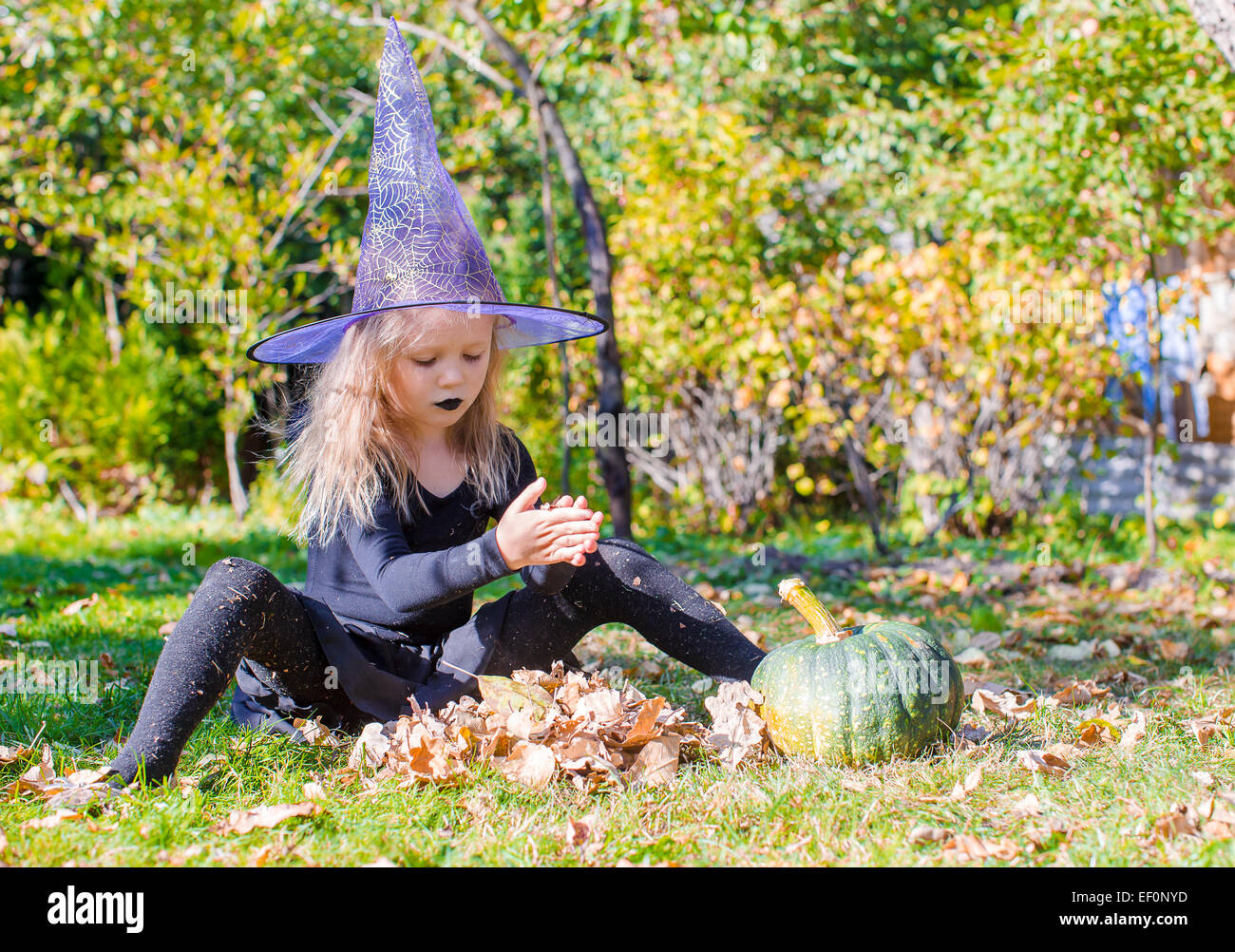 Little cute girl casts a spell on Halloween in witch costume Stock ...