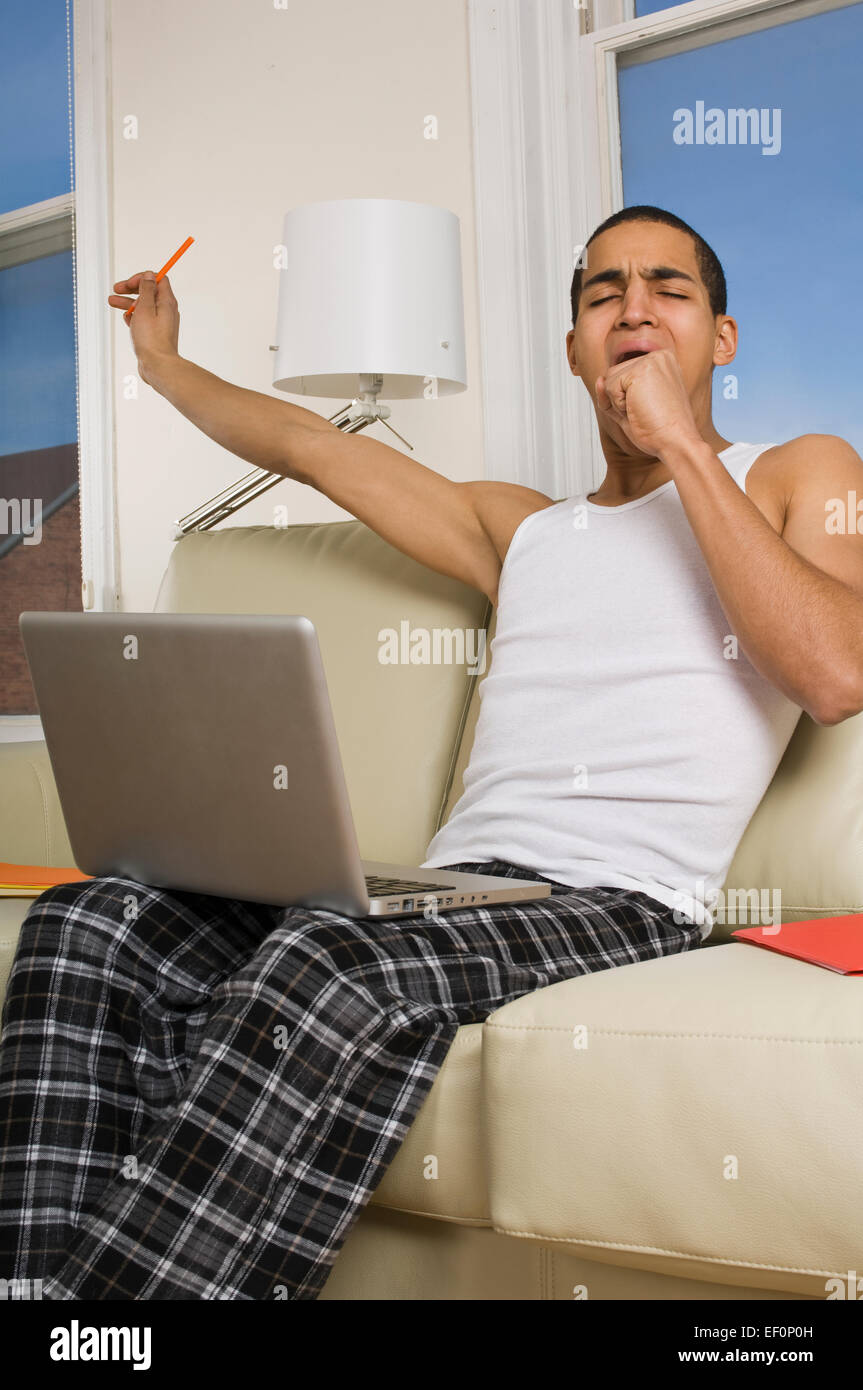 Tired man sitting on couch with laptop Stock Photo