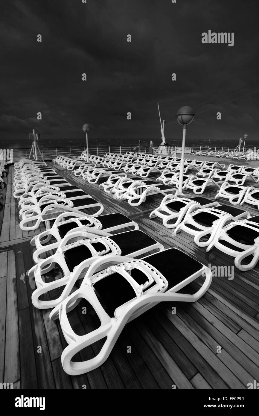 Sun loungers on a cruise ship deck in stormy seas and dramatic clouds ...