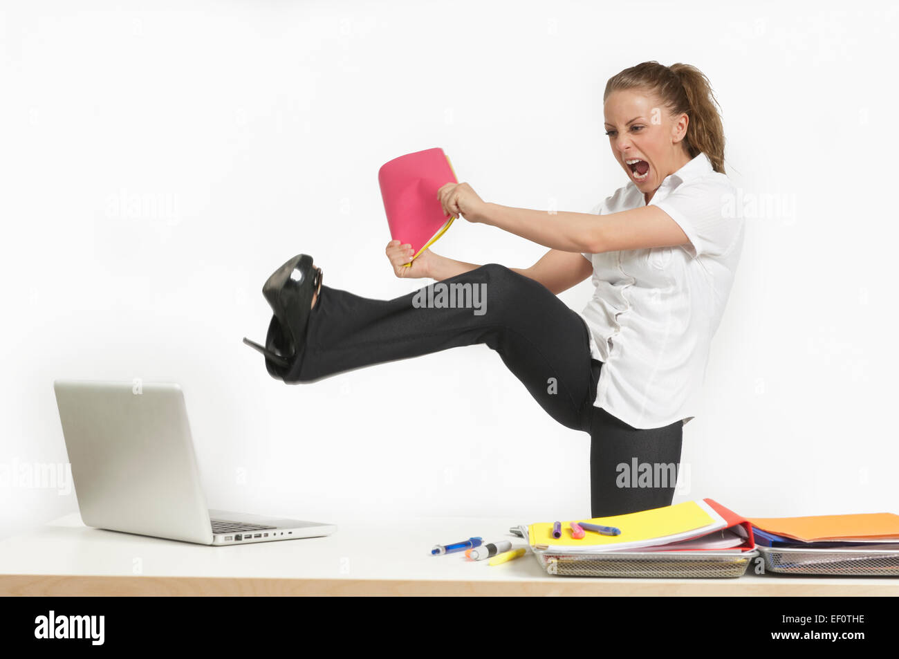 Angry woman kicking her leg towards laptop Stock Photo