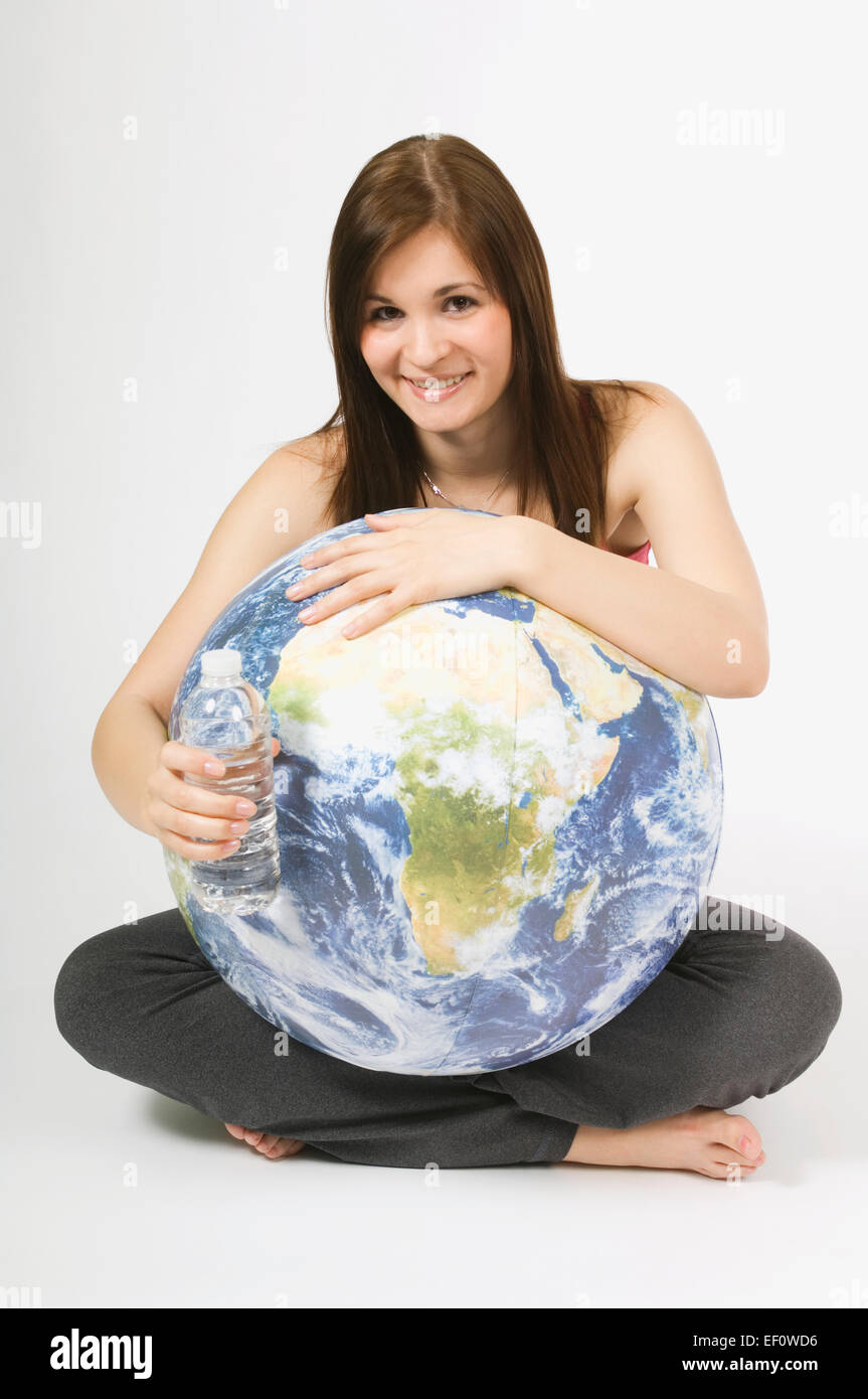 Woman holding a globe and a plastic water bottle Stock Photo