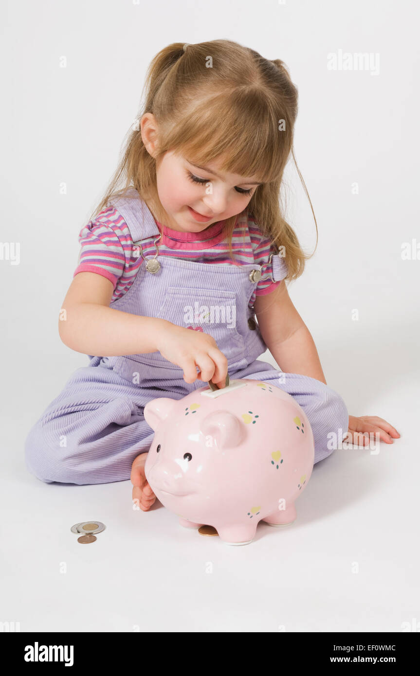 Young girl putting coins in a piggy bank Stock Photo
