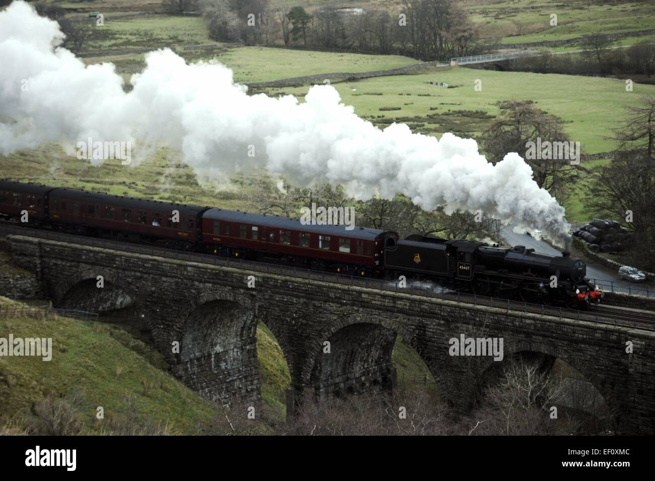 Pennines, Cumbria, UK. 24th January, 2015. UK milder weather. The Cumbrian Winter Mountain Express steams through the melting snow of the Pennines of Cumbria as temperatures get milder. The first special steam hauled train of 2015 on the historic Carlisle to Settle railway line. Locomotive No. 45407 'The Lancashire Fusilier' climbs over Ais Gill Viaduct making a good head of steam on the long climb to the summit of Ais Gill which at 1,169 feet is the highest railway summit in England.   Credit:  STUART WALKER/Alamy Live News Stock Photo