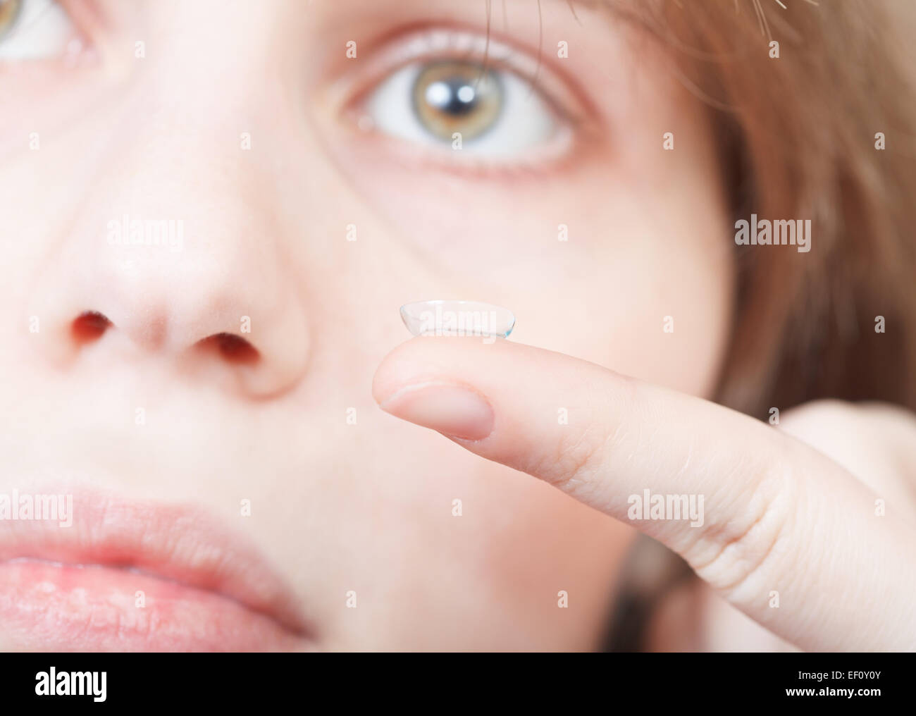 finger with corrective lens close up and female face backhround Stock Photo