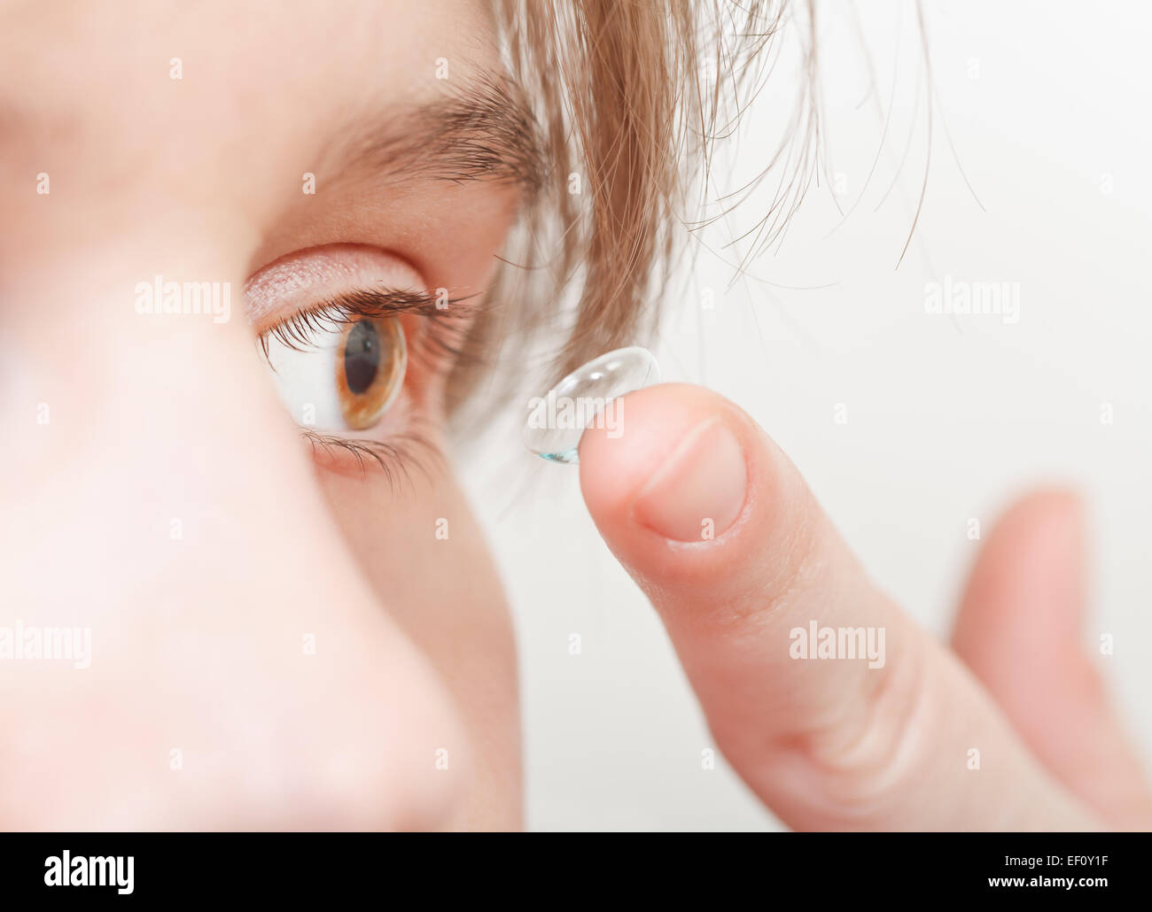young woman inserts corrective lens in eye close up Stock Photo
