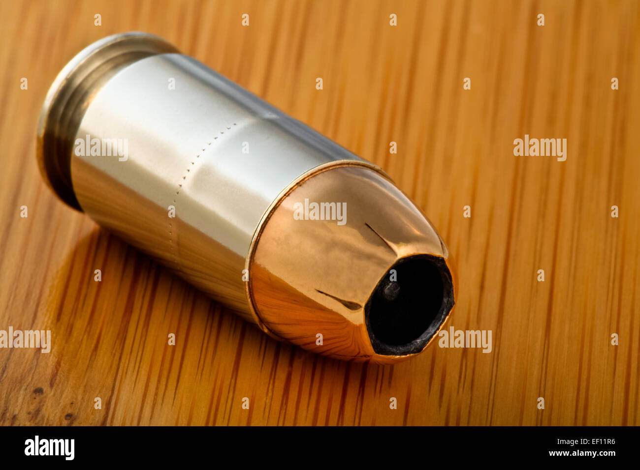 Closeup 45 caliber jacketed hollow point bullet cartridge live round for semi-automatic handgun gun with bamboo wood background Stock Photo