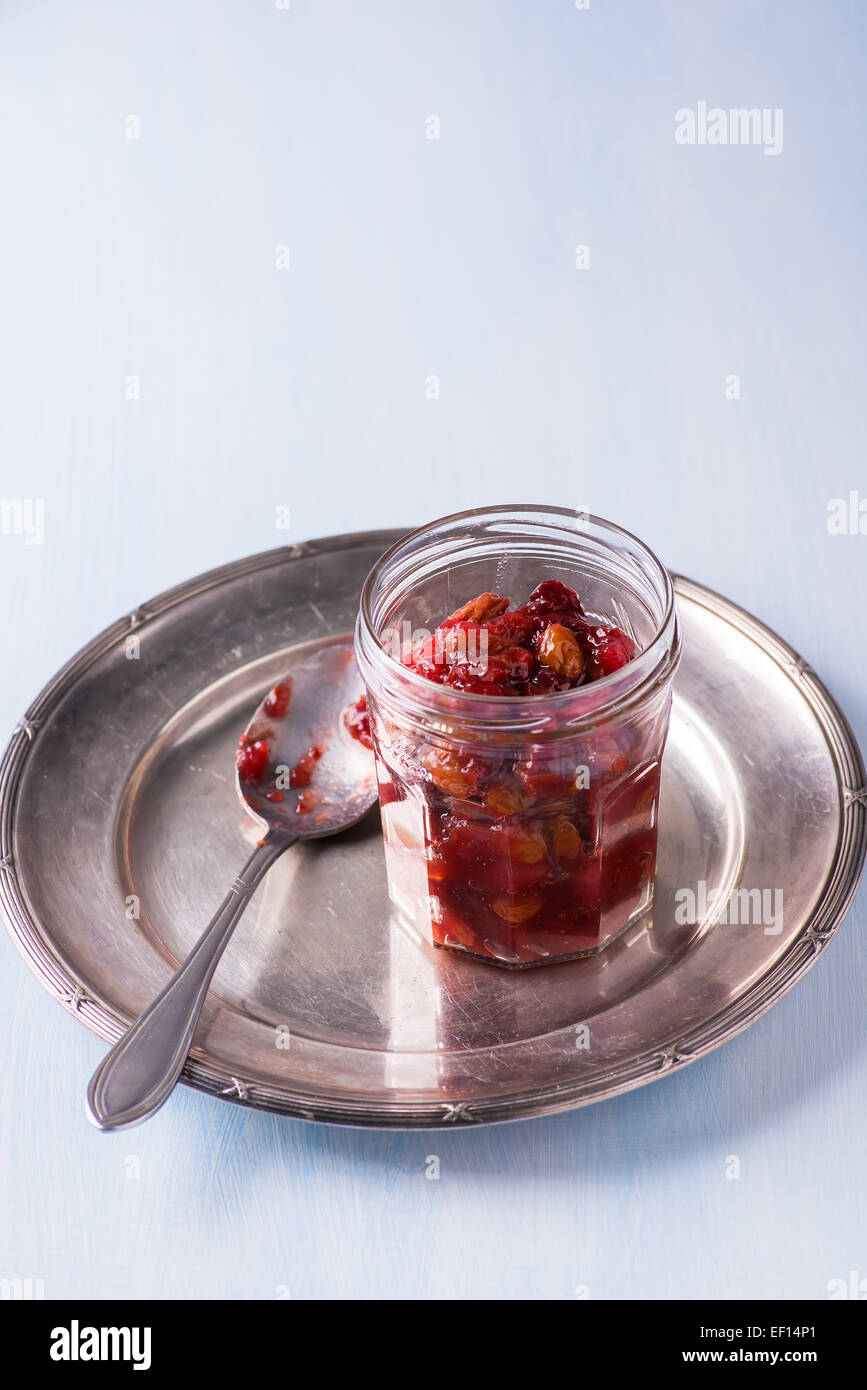 Pear cranberry relish in jar on vintage metal plate over light blue background, copy space Stock Photo