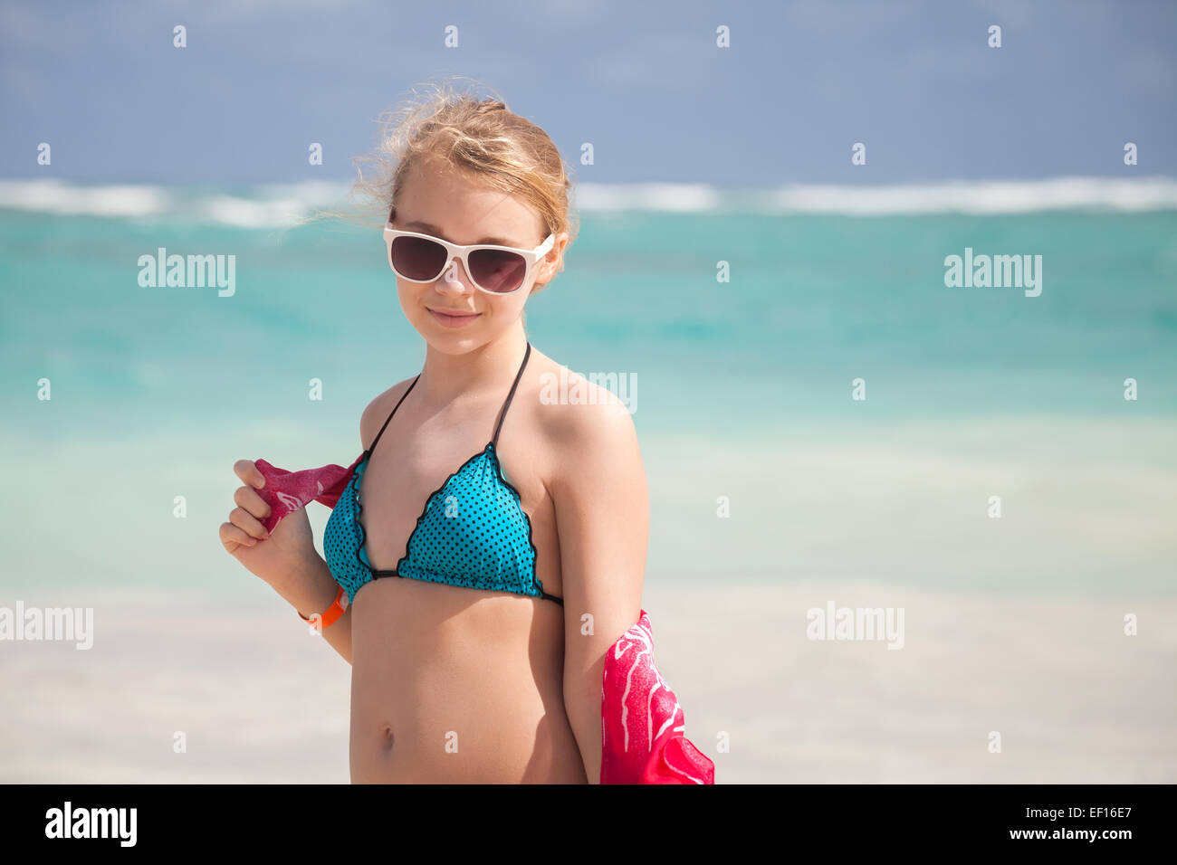 Outdoor portrait of beautiful Caucasian teen girl in blue swimsuit and red shawl on the ocean coast Stock Photo